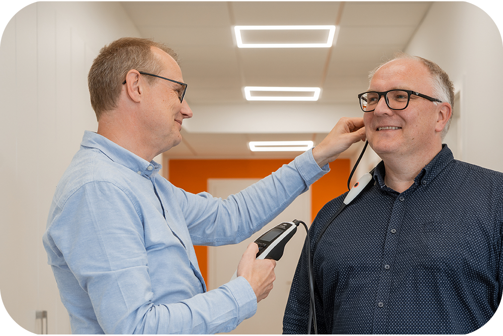 hoertest-messung-freisprechmikrofon-praxis_mobile Akustiker führt Hörtest mit Messgerät durch, Kunde trägt Messmikrofon, präzise Anpassung, Hörakustik.